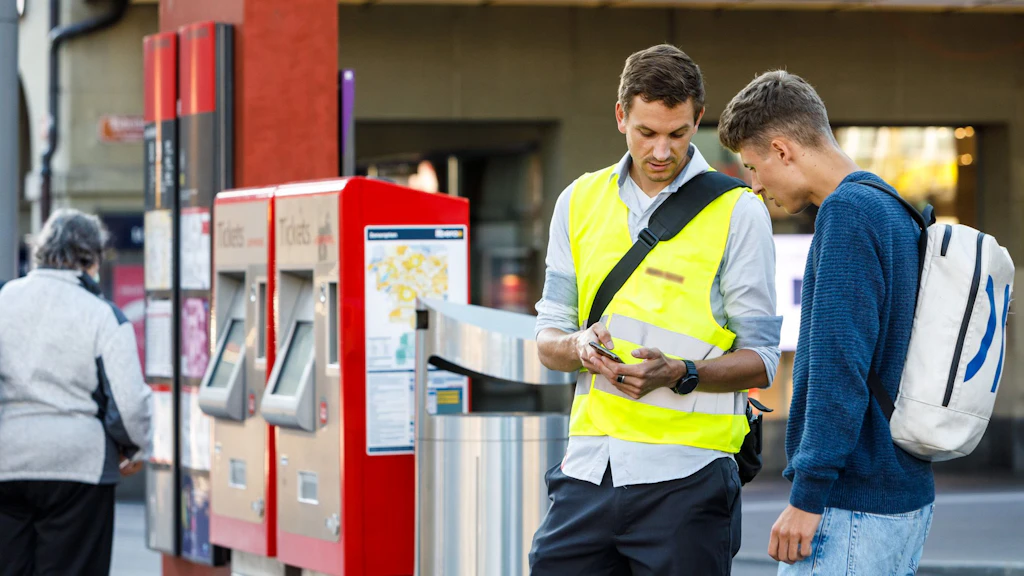 Ein Mitarbeiter eines öV-Unternehmens spricht mit einem Passagier